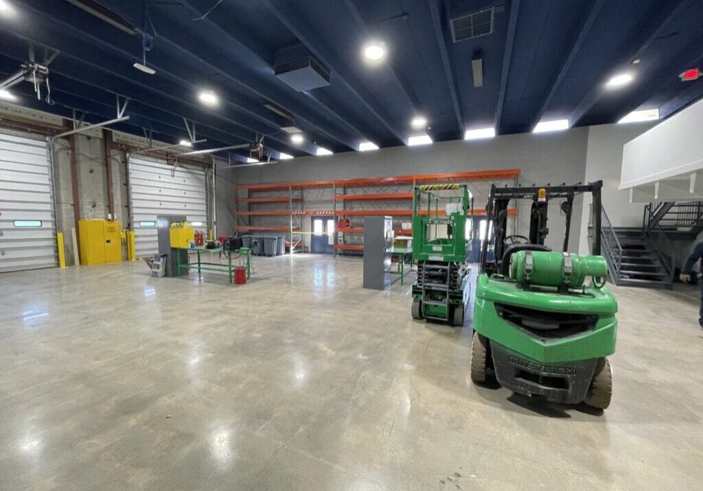 A warehouse with many forklifts parked in it.